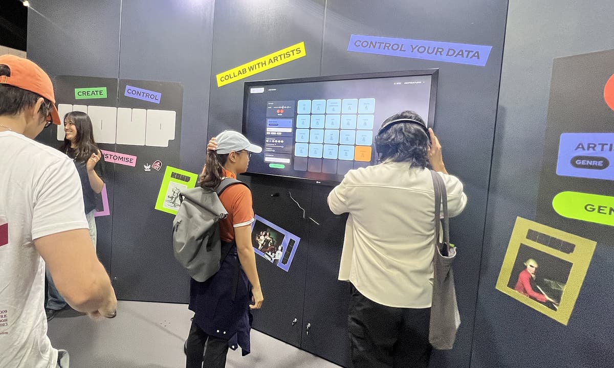 A group of people gathered in a booth at SXSW, looking at and interacting with the KOUP interface displayed on a screen.